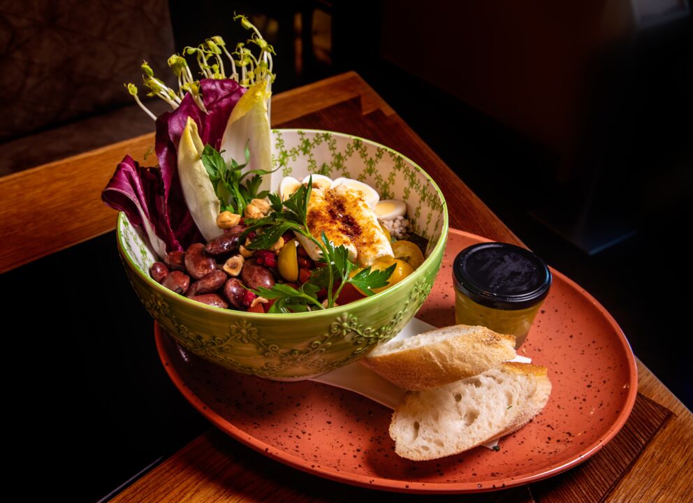 Das Restaurant Benediktus am Mondsee serviert eine Bowl mit Bohnen, Salat, etwas Fleisch und ein paar Scheiben Brot.